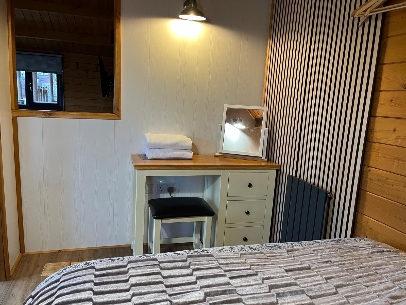 A bedroom with a bed , dresser , mirror and heart hanging on the wall.