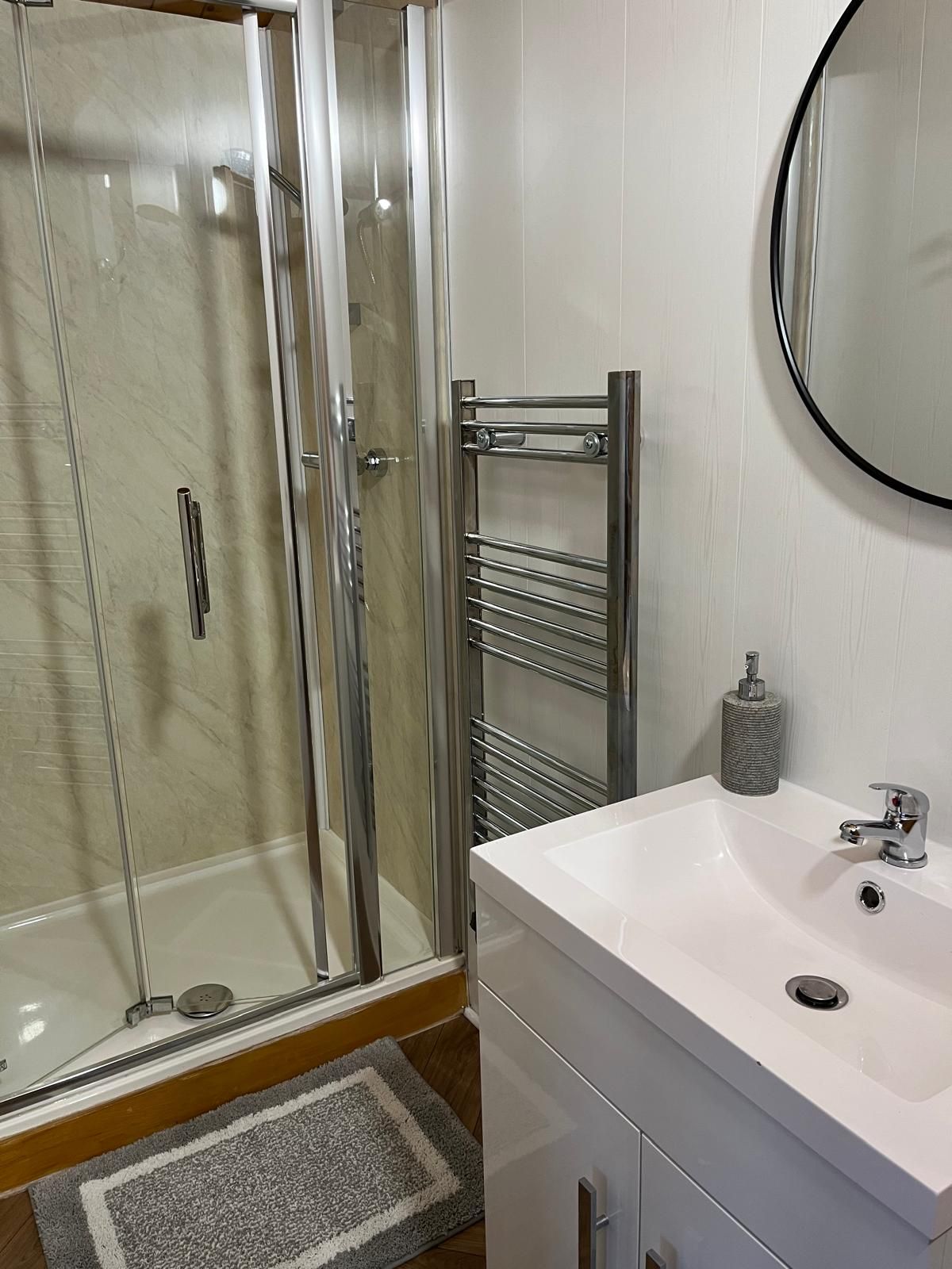 A bathroom with a sink , shower and mirror.