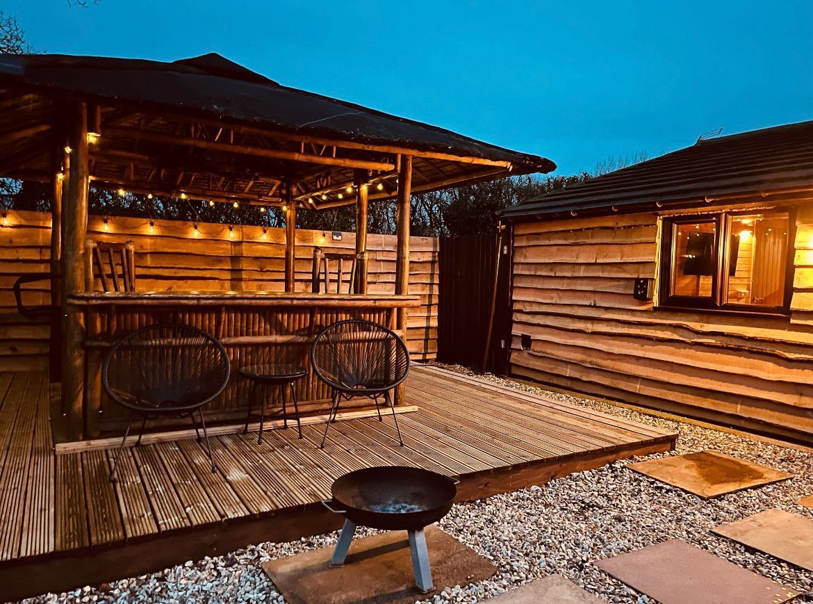 A wooden gazebo with a picnic table in front of it