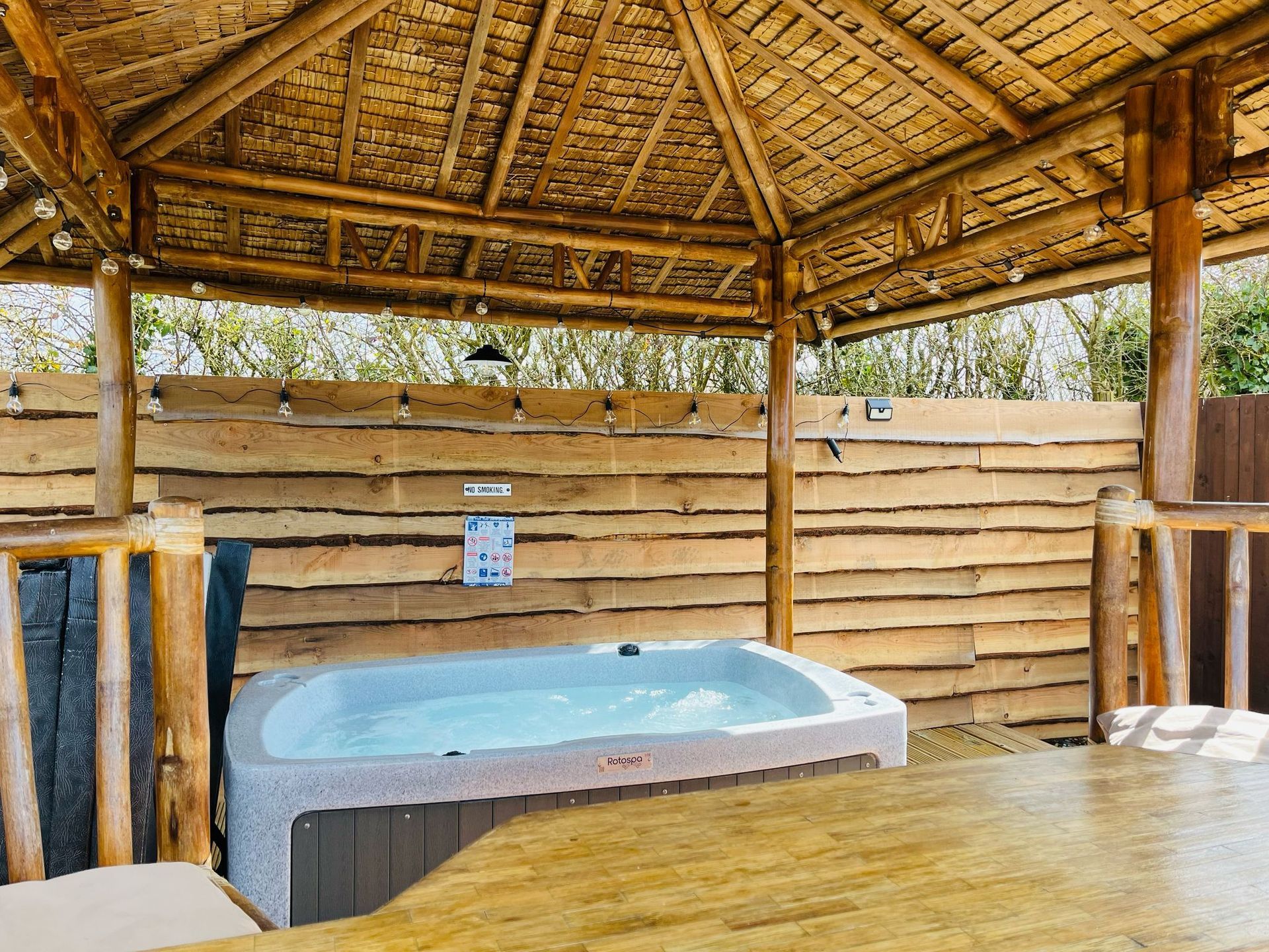 A hot tub is sitting on a wooden deck next to a wooden bar.