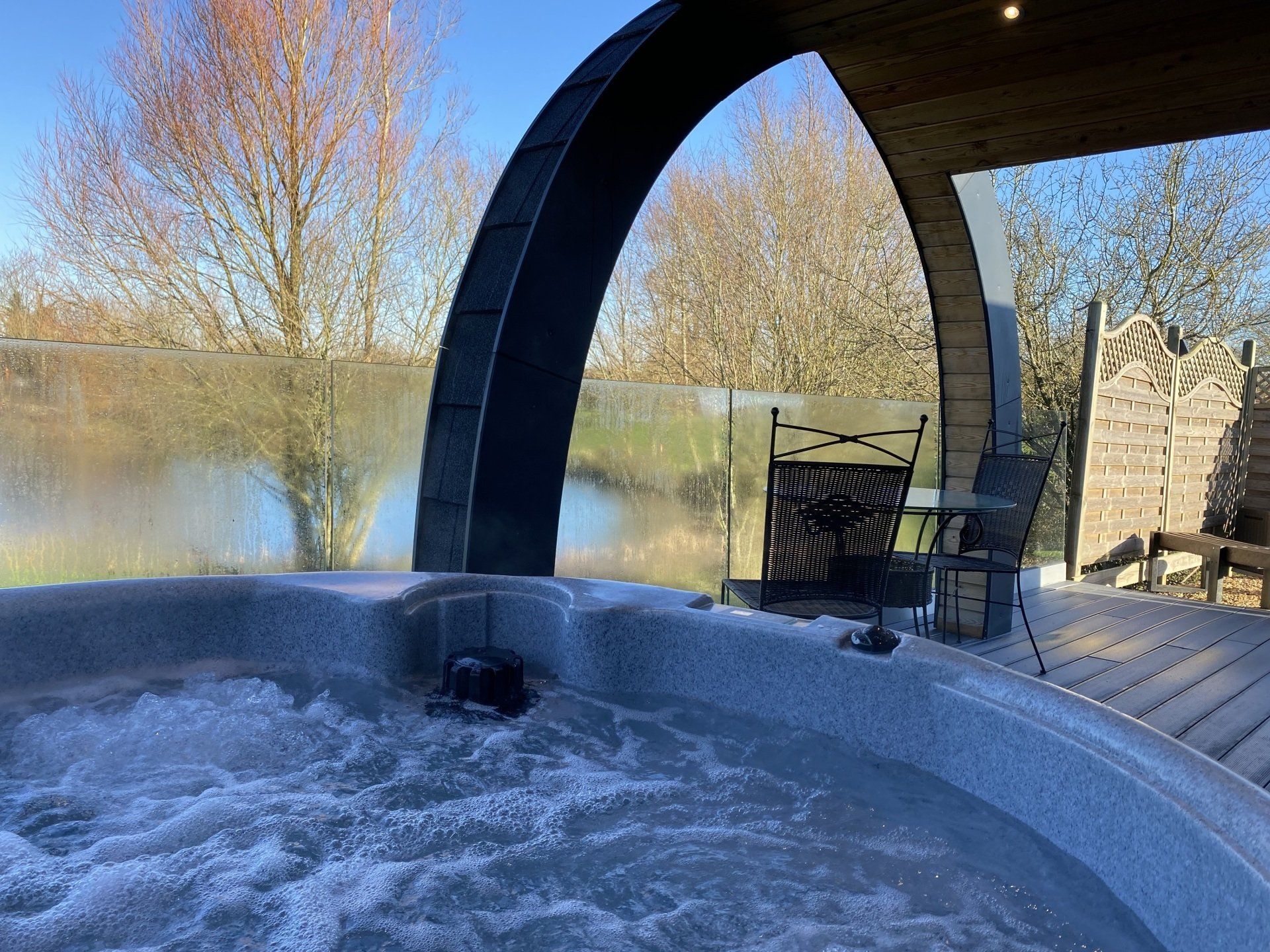 A hot tub with a view of a lake is on a deck.