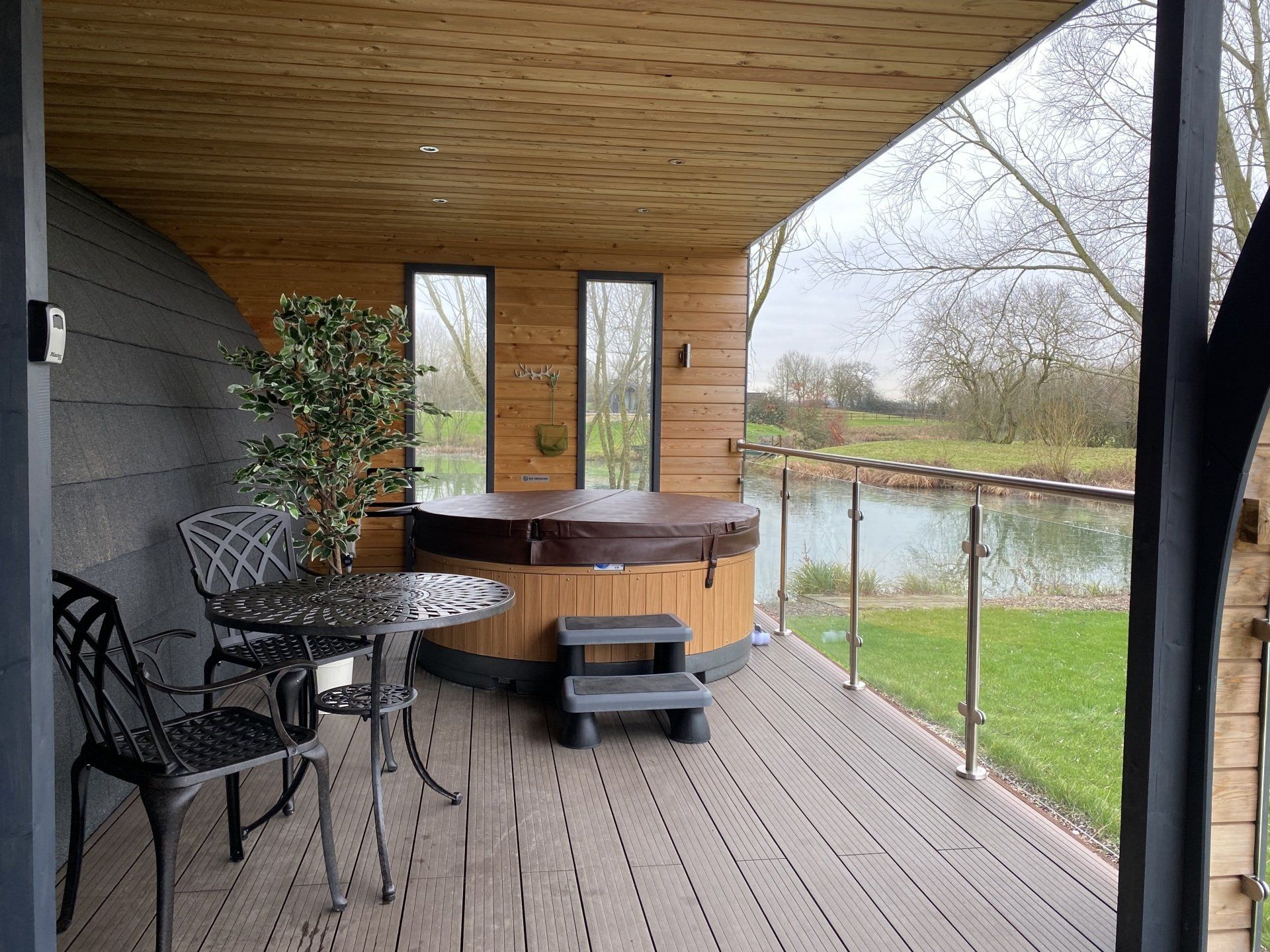 There is a hot tub on the deck with a table and chairs.