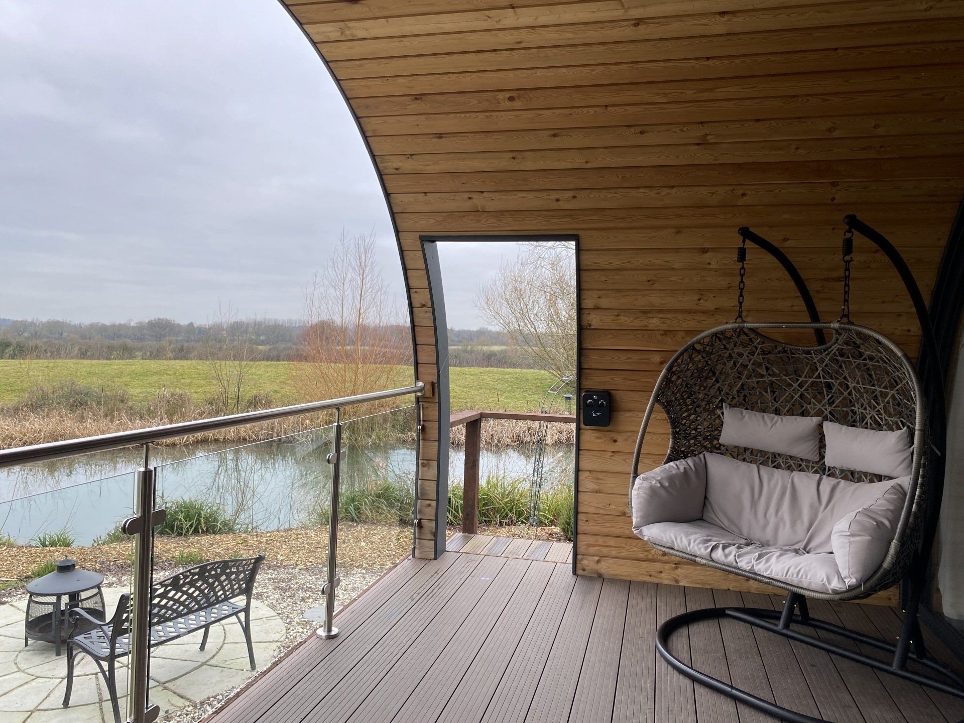 A wooden deck with a hanging chair and a bench.