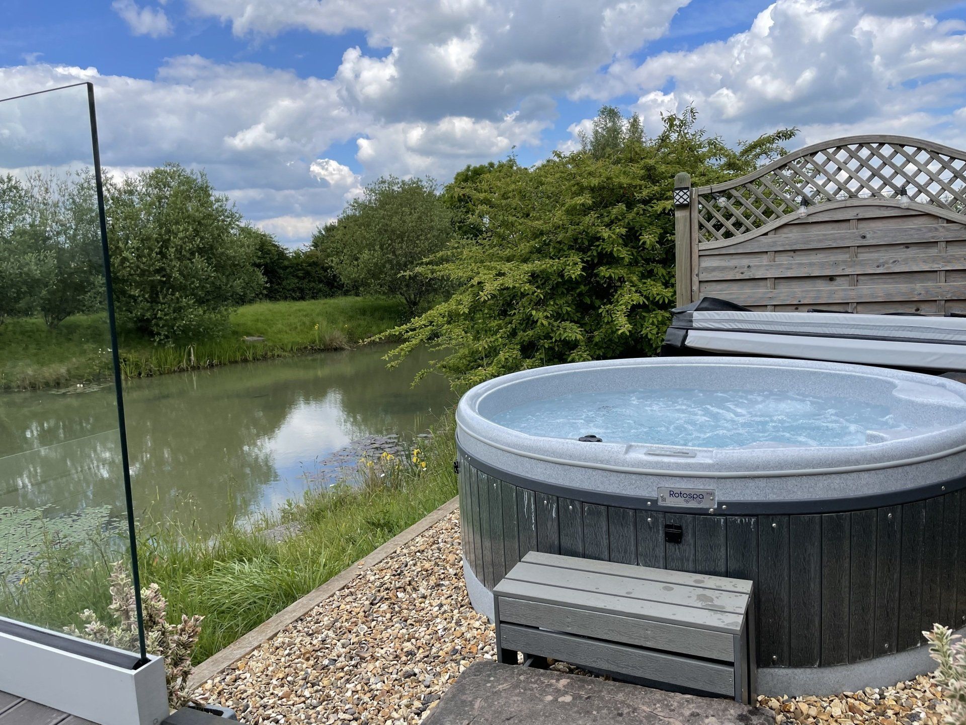 A hot tub is sitting on a patio next to a river.