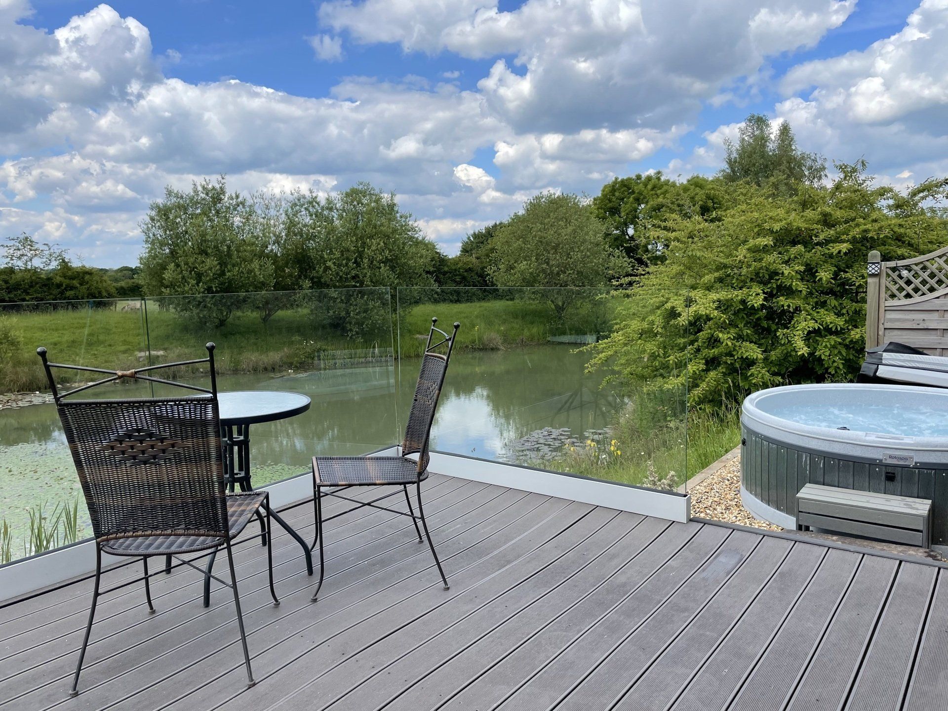 There is a table and chairs on the deck with a hot tub in the background.