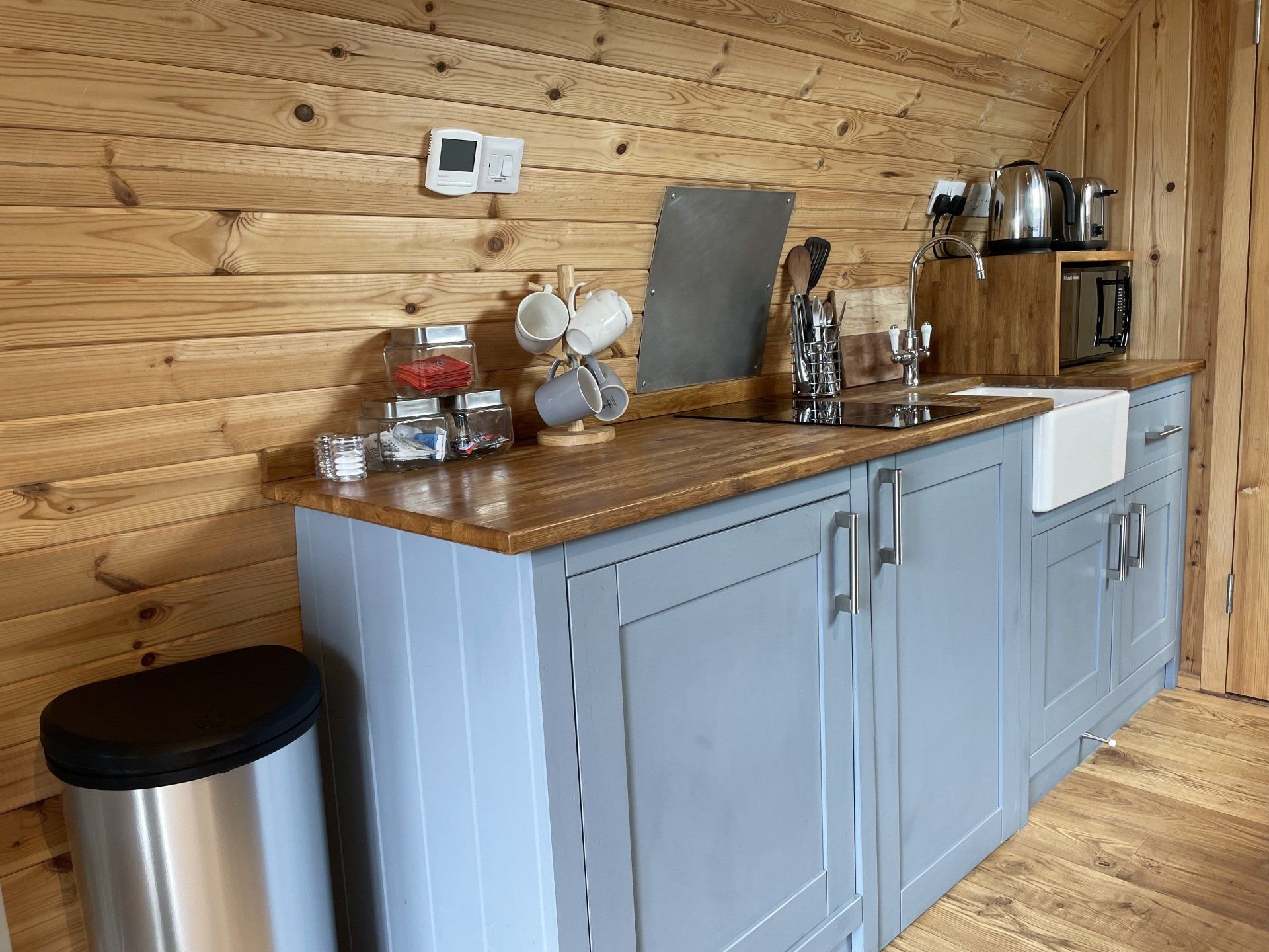 A kitchen with a sink , cabinets , and a trash can.