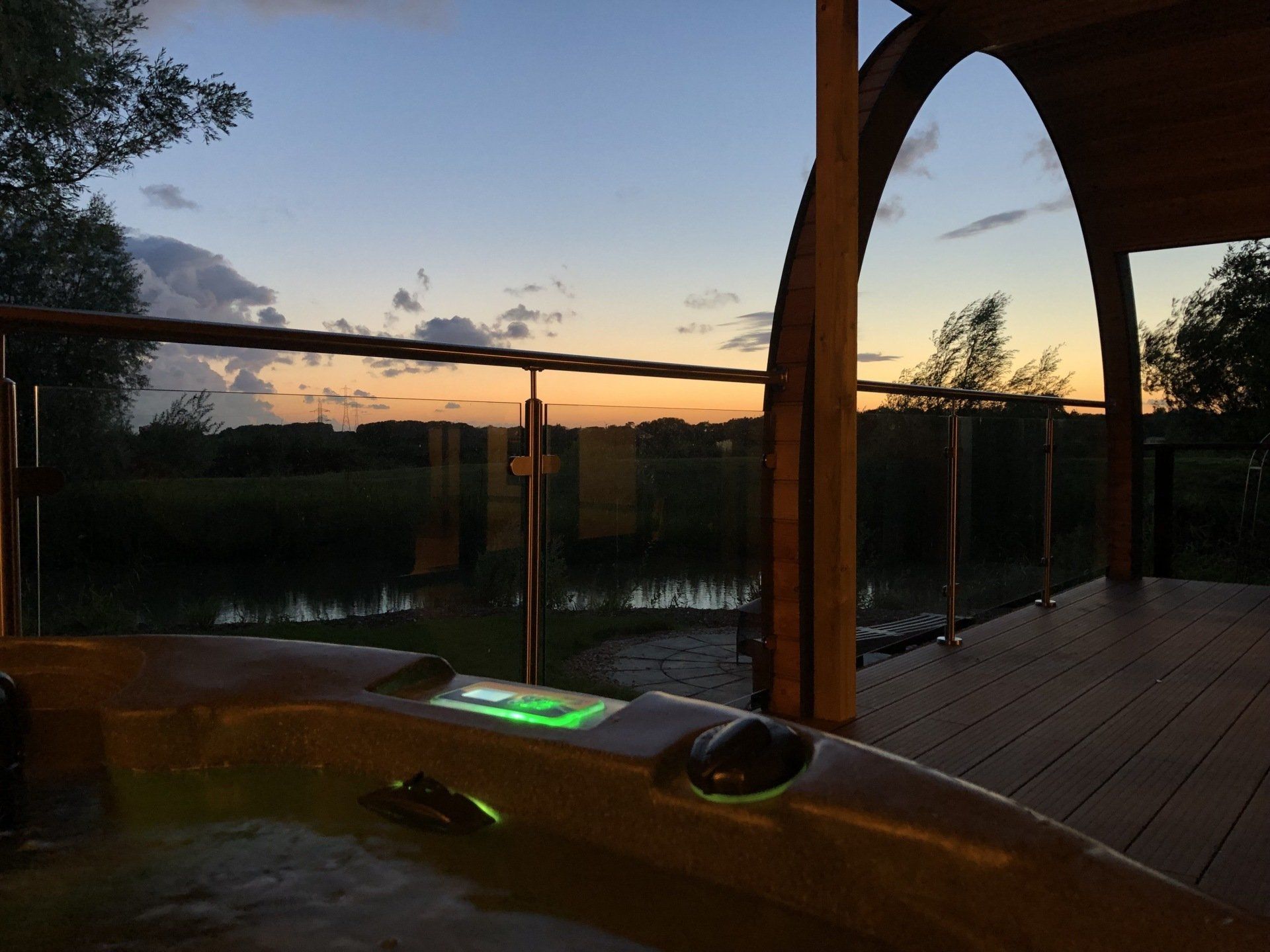 A hot tub on a deck overlooking a body of water at sunset