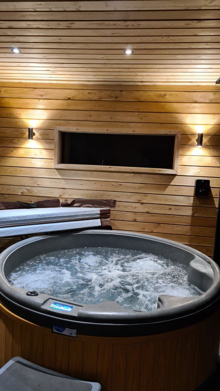 A hot tub is sitting in a wooden room next to a wooden wall.