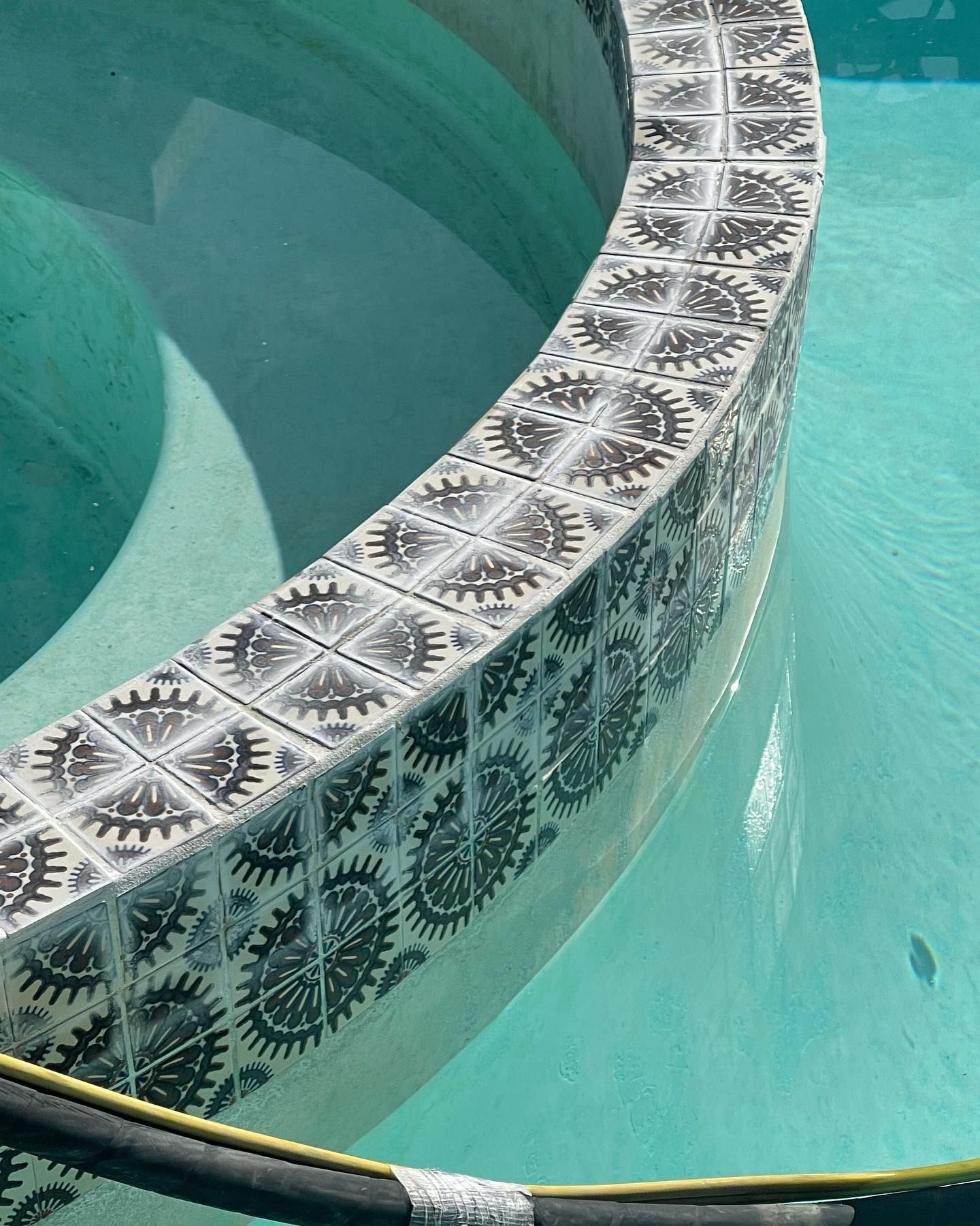 A swimming pool with a black and white tile border