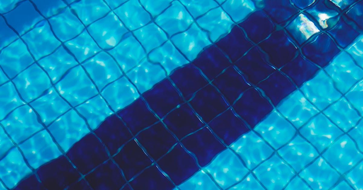 A person is swimming in a swimming pool with blue tiles.