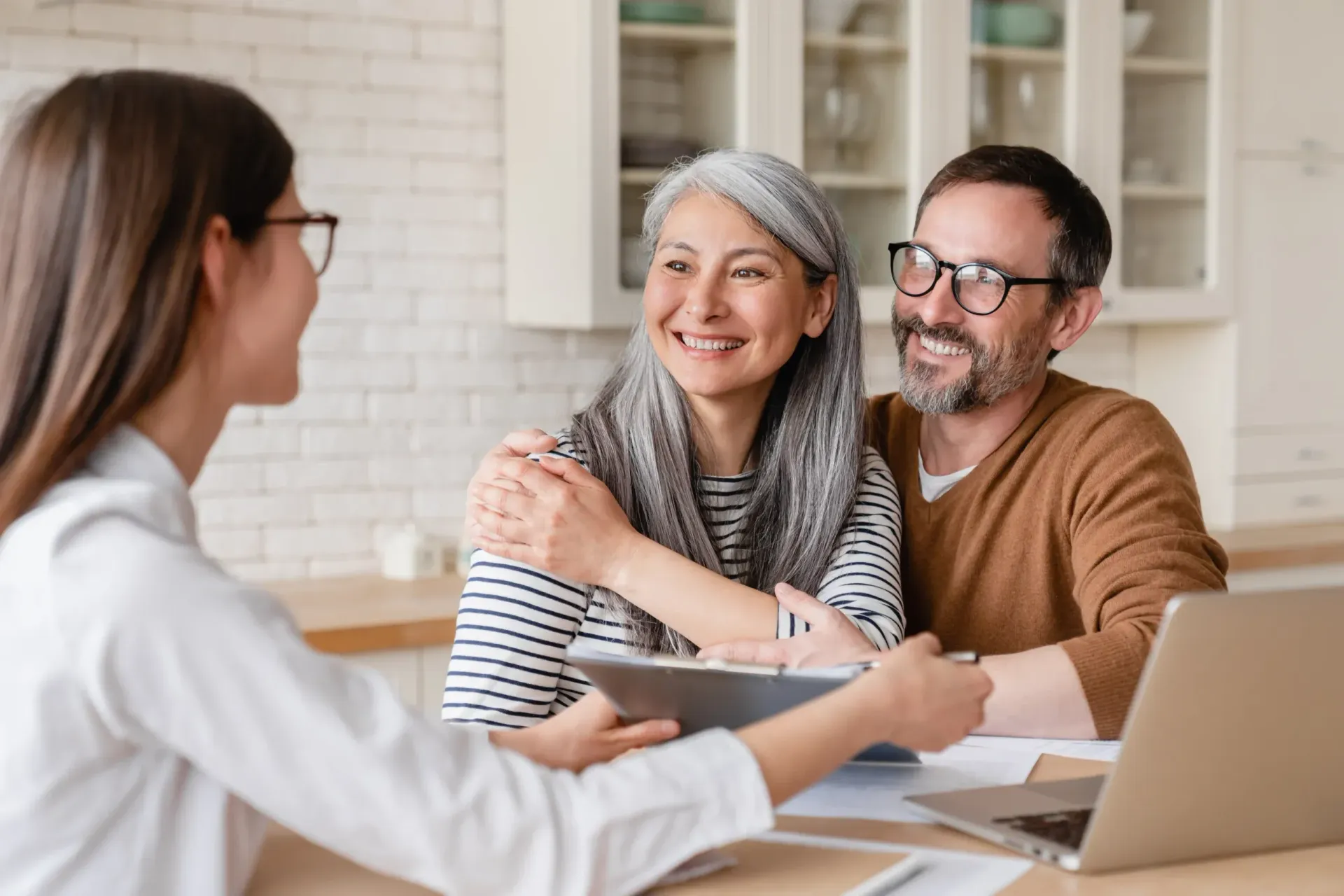 Counselor meeting with a smiling couple at a desk in a bright office