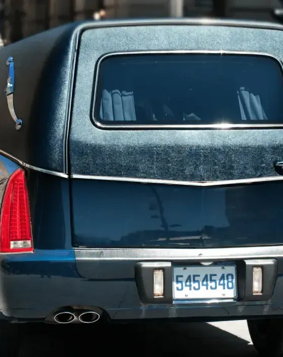 Dark blue hearse with silver trim and rear window, parked with visible license plate.