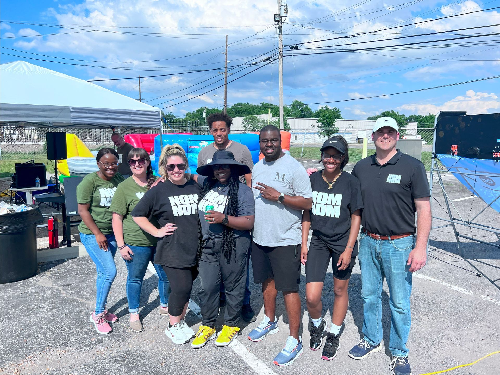 Group of people posing outdoors in front of a tent. They're wearing t-shirts that say