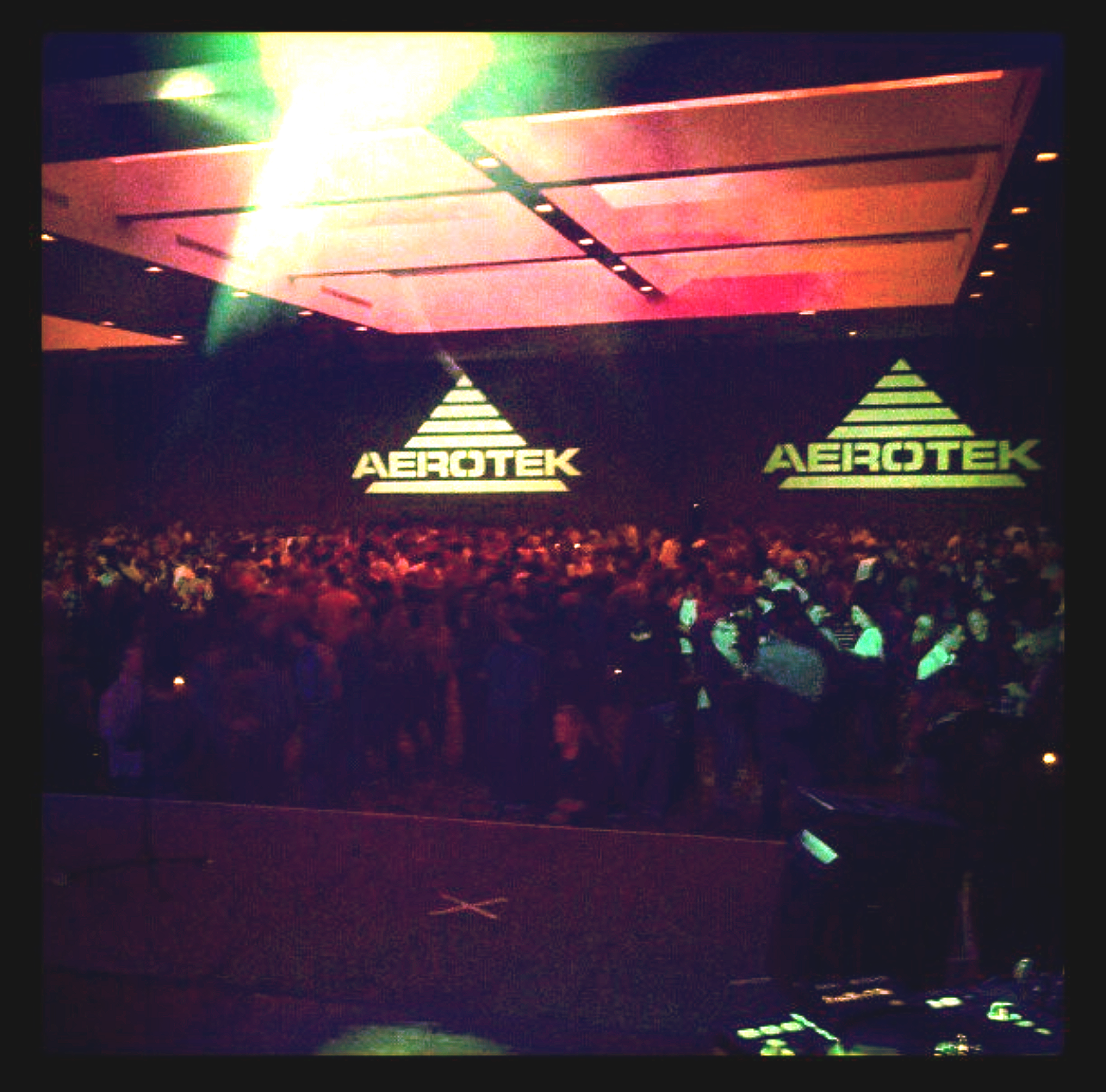Large crowd at an Aerotek event; stage with Aerotek logos, bright lights, people facing stage.