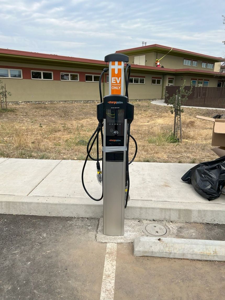 Close-up of two black electric vehicle charging connectors on a charging station outdoors.