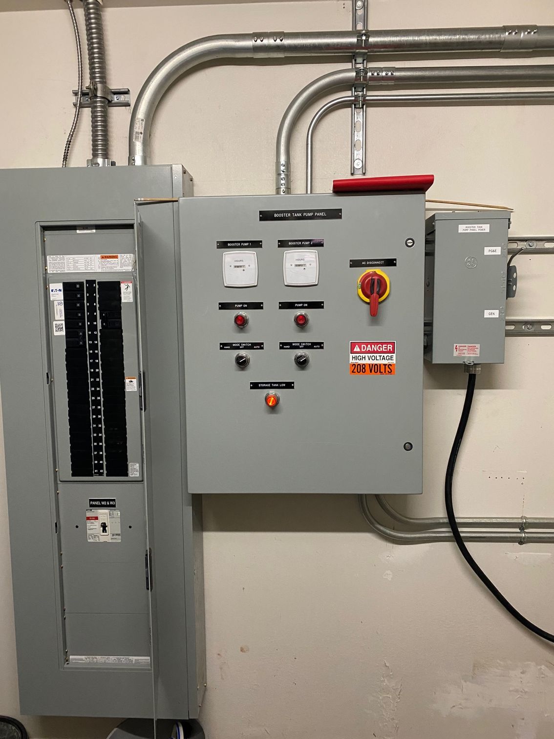 Electrical control panels and disconnect switches mounted on a wall with conduit piping.
