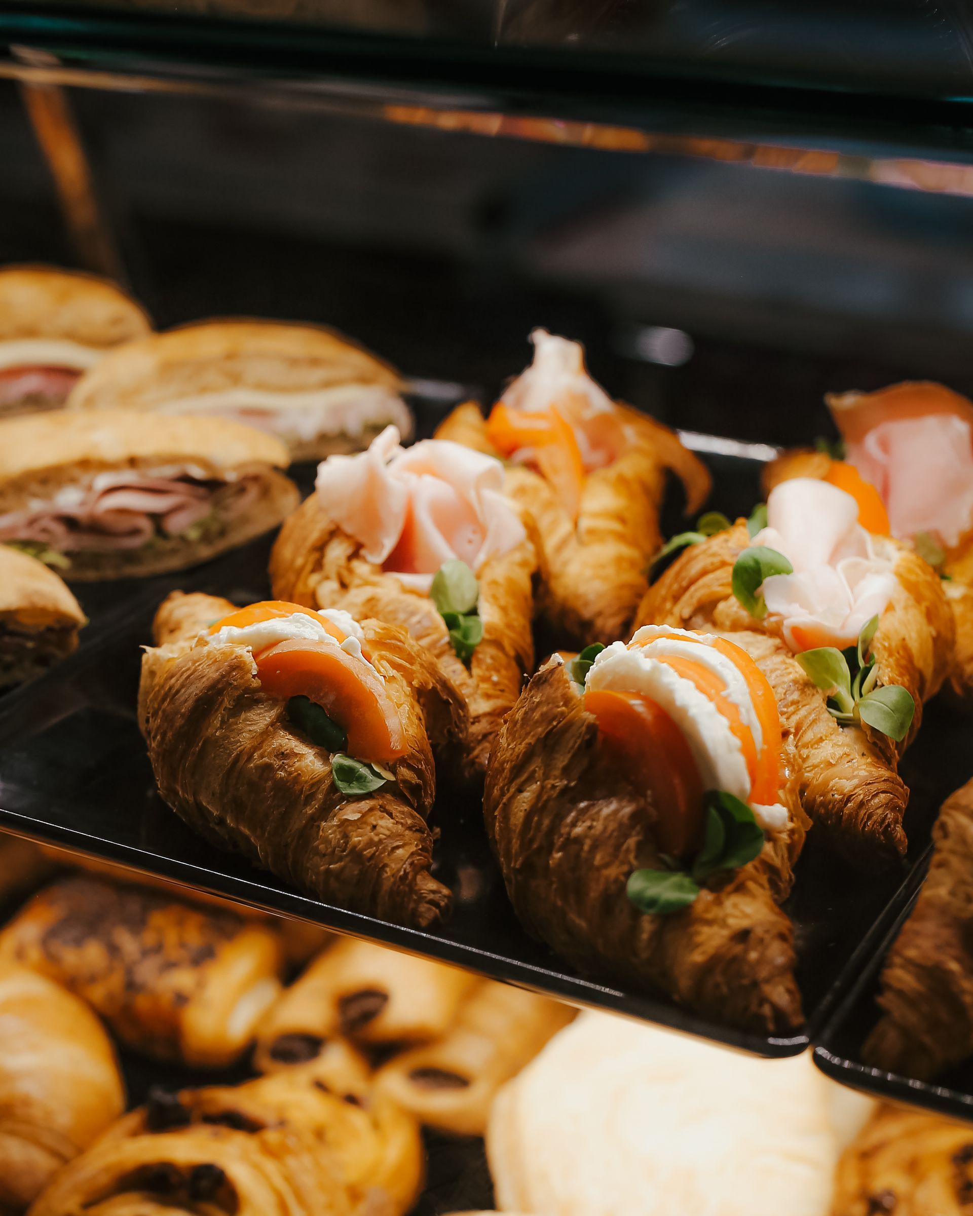 Assortimento di pasticcini ripieni di crema su un vassoio da pasticceria, spolverati di zucchero a velo e guarniti con frutta.