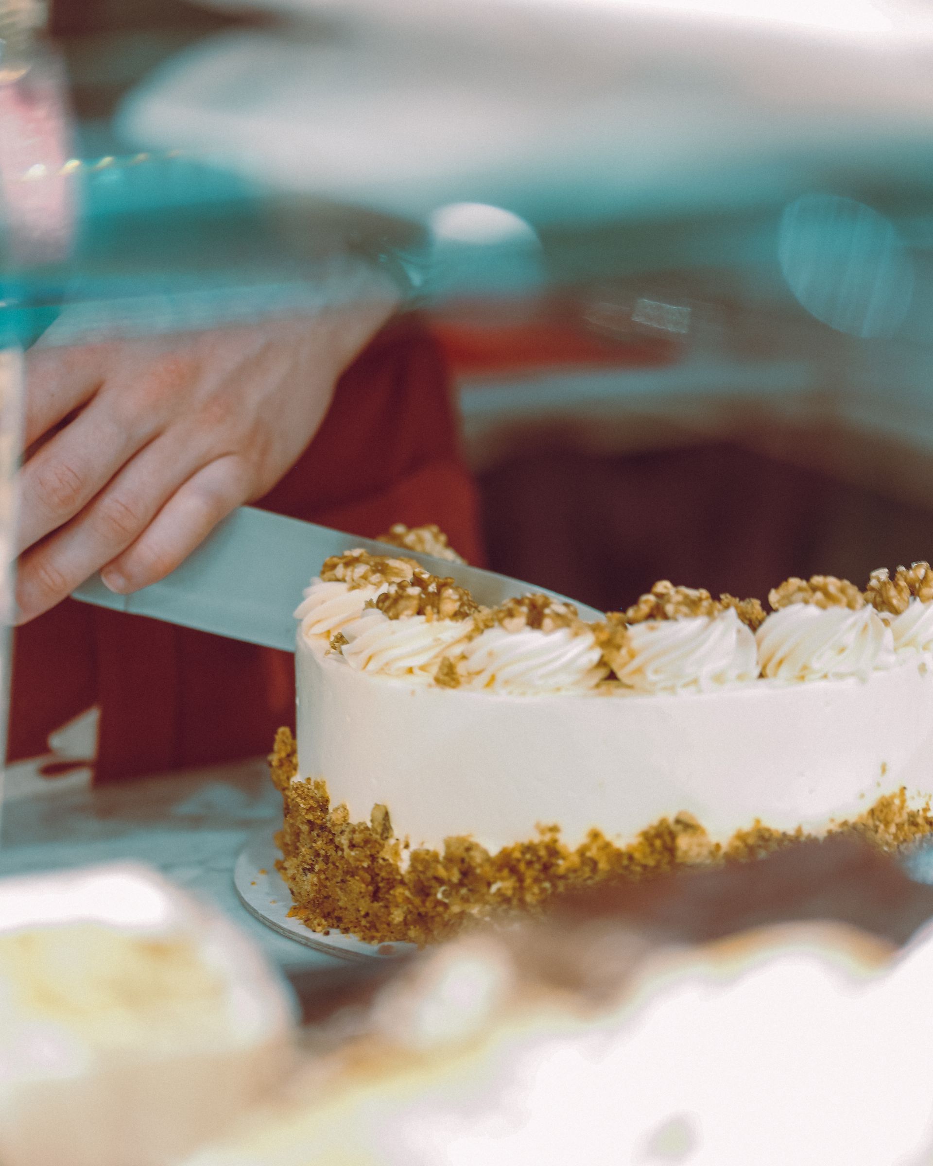Mani che glassano una torta bianca con briciole dorate su un tavolo