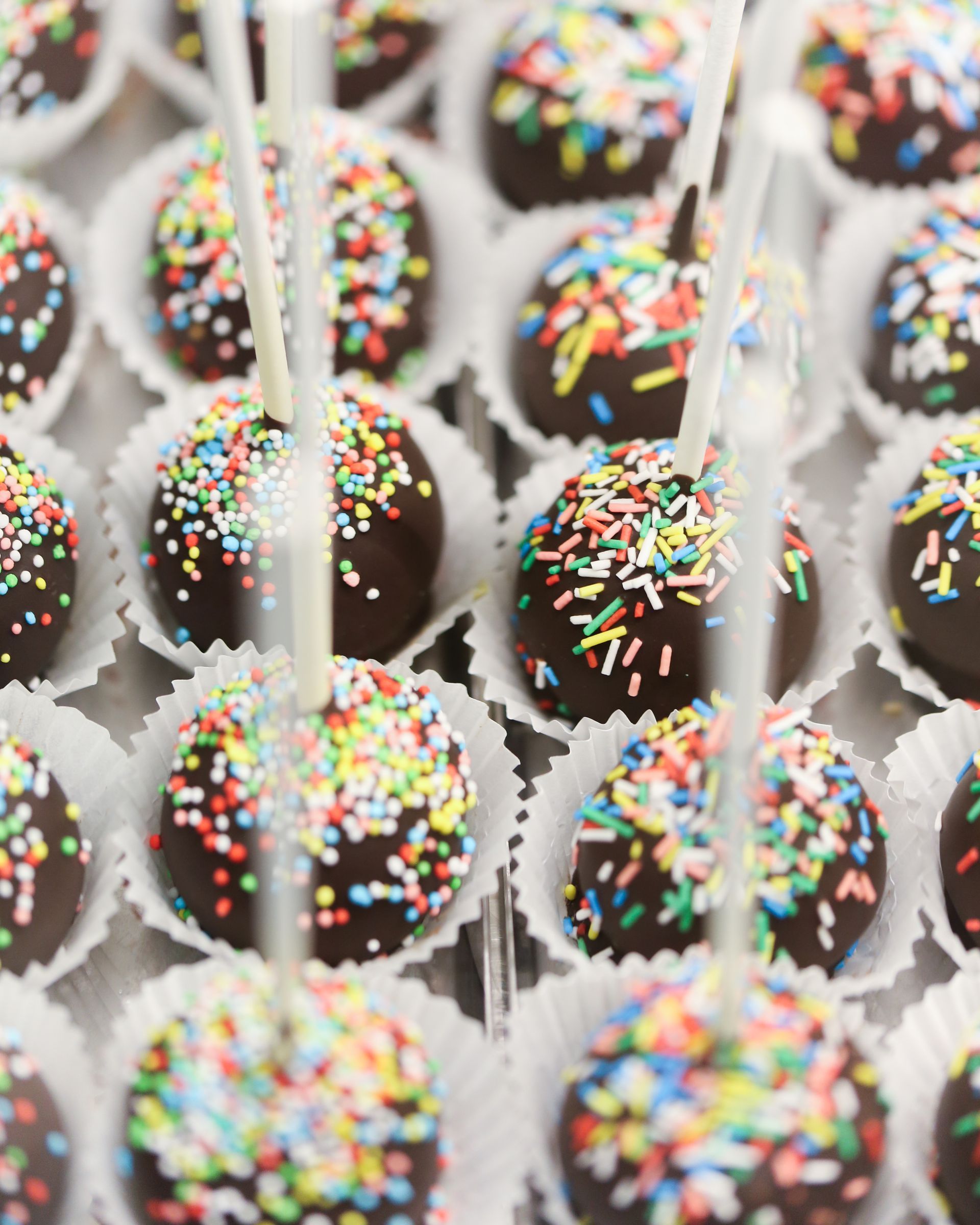 Cake pops al cioccolato con zuccherini colorati in pirottini di carta bianchi