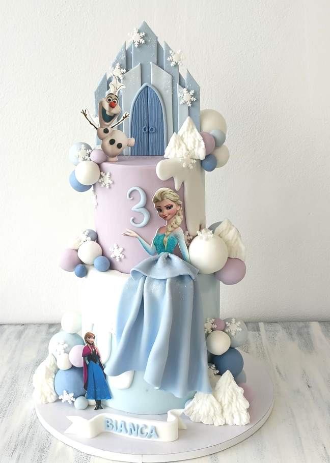 Decorazione per torta a tema Frozen con Elsa, il numero 3 e il nome Bianca su una torta nei toni del blu pastello e del rosa.