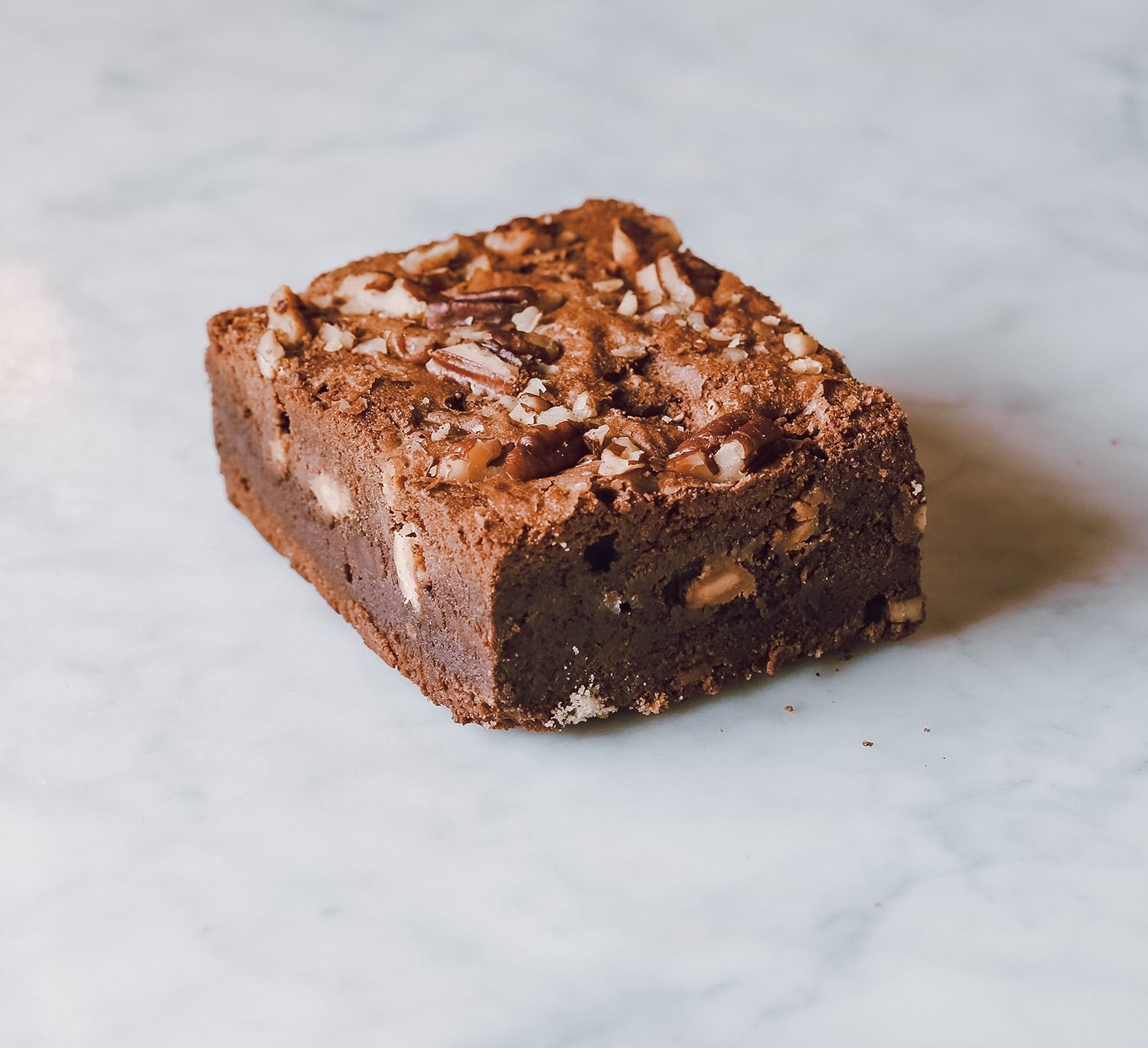 Brownie al cioccolato con copertura di noci su una superficie di marmo bianco