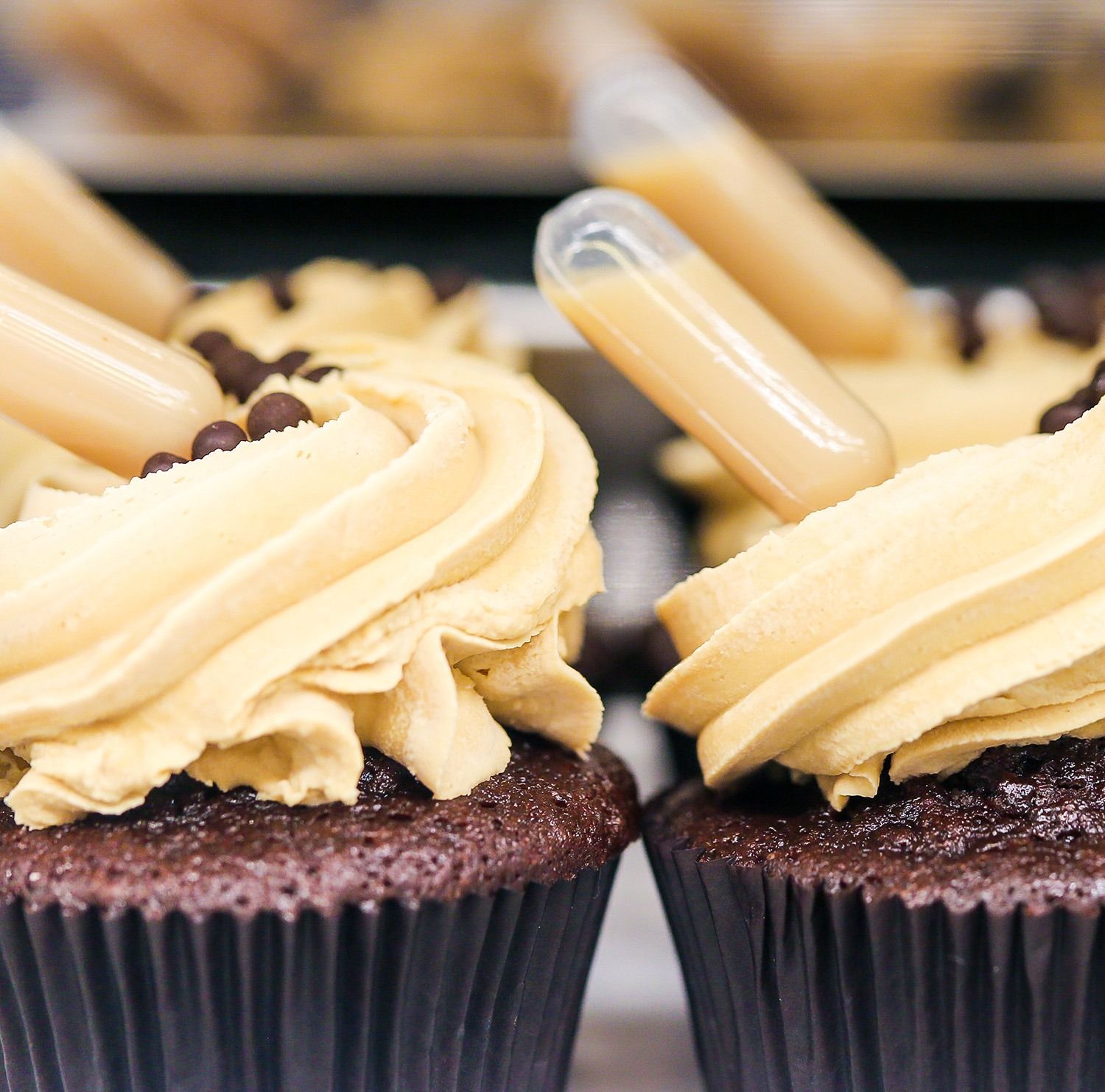 Cupcake al cioccolato guarniti con glassa alla vaniglia a spirale e pezzetti di caramelle bianche.