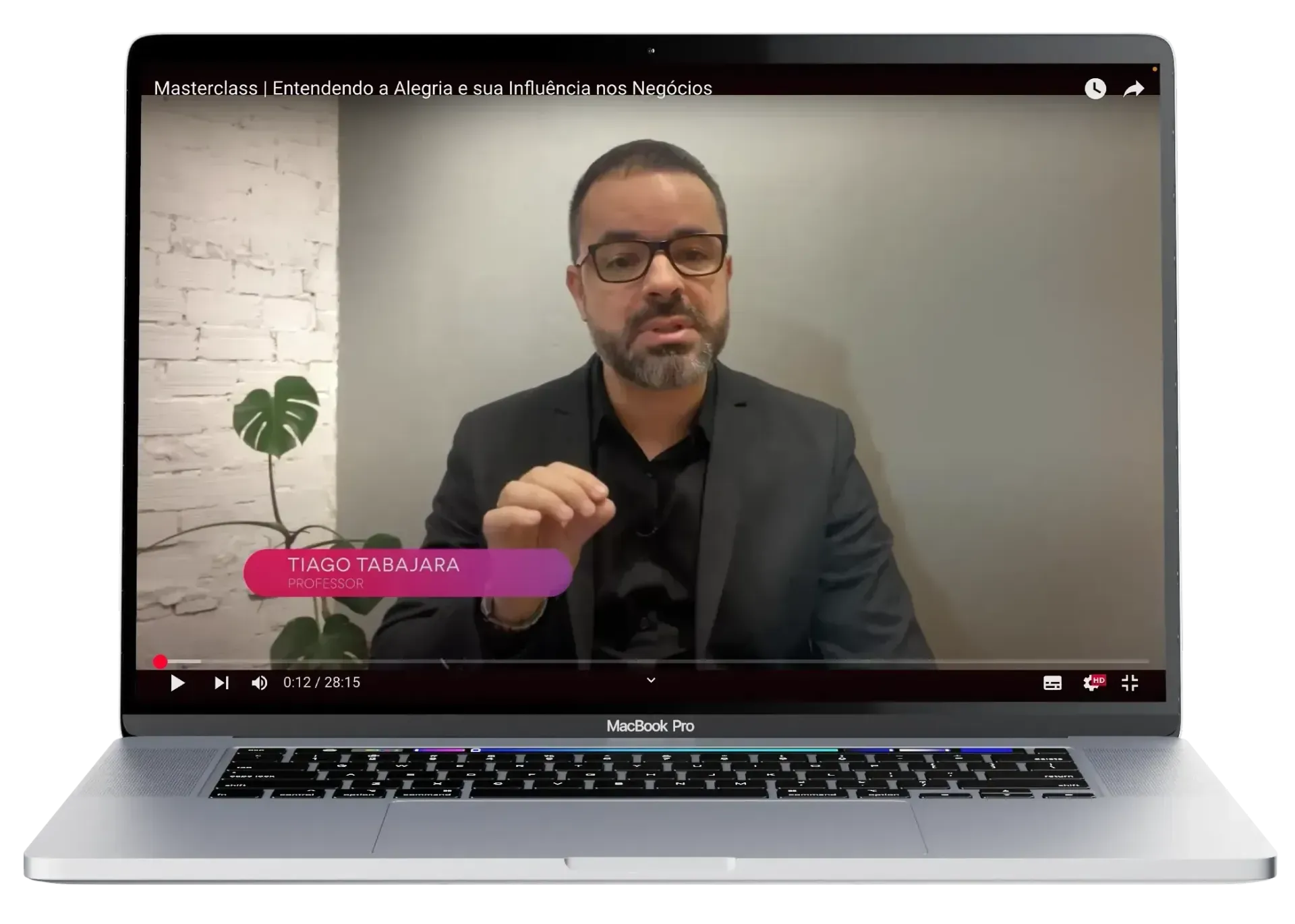 Um homem de terno e óculos está sentado em frente a um laptop.