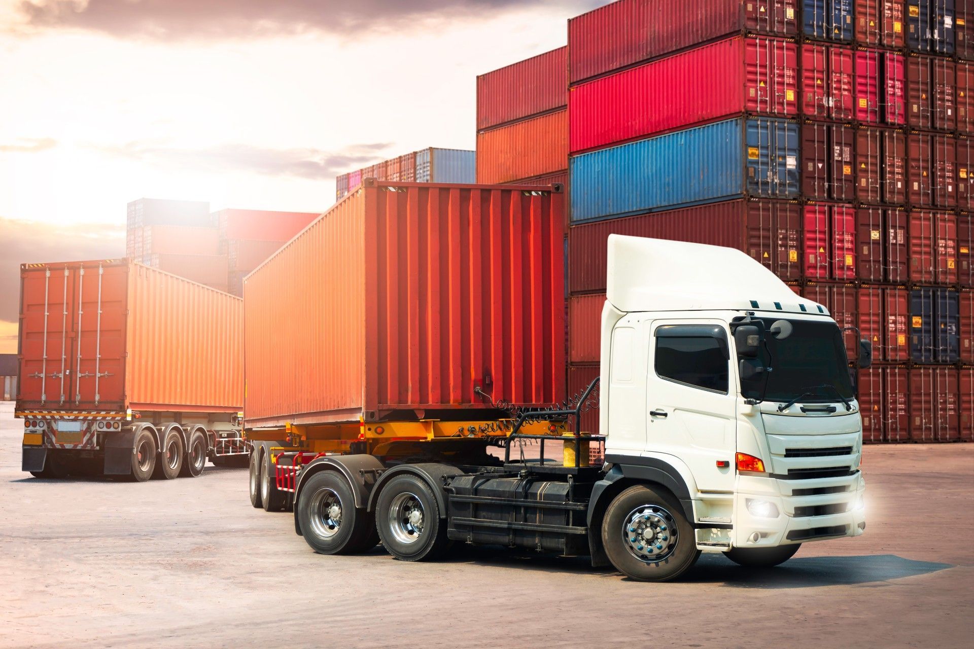 A semi truck is parked in front of a row of shipping containers.