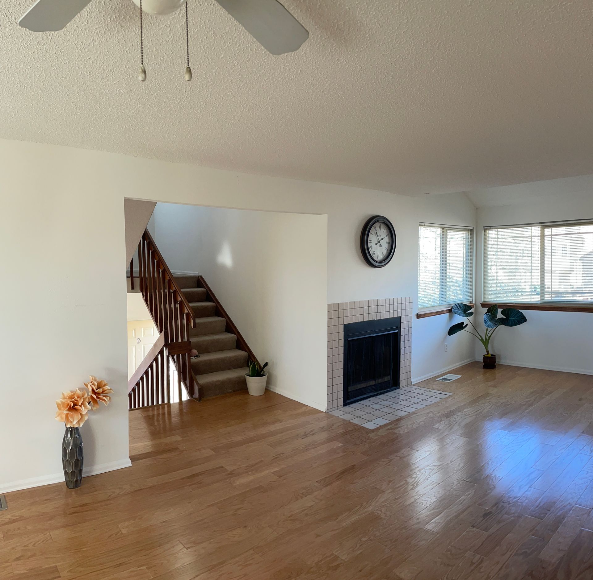 An empty living room with a fireplace and a ceiling fan.