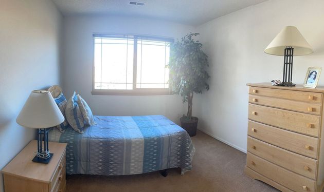A bedroom with a bed , dresser , nightstand , lamp and window.