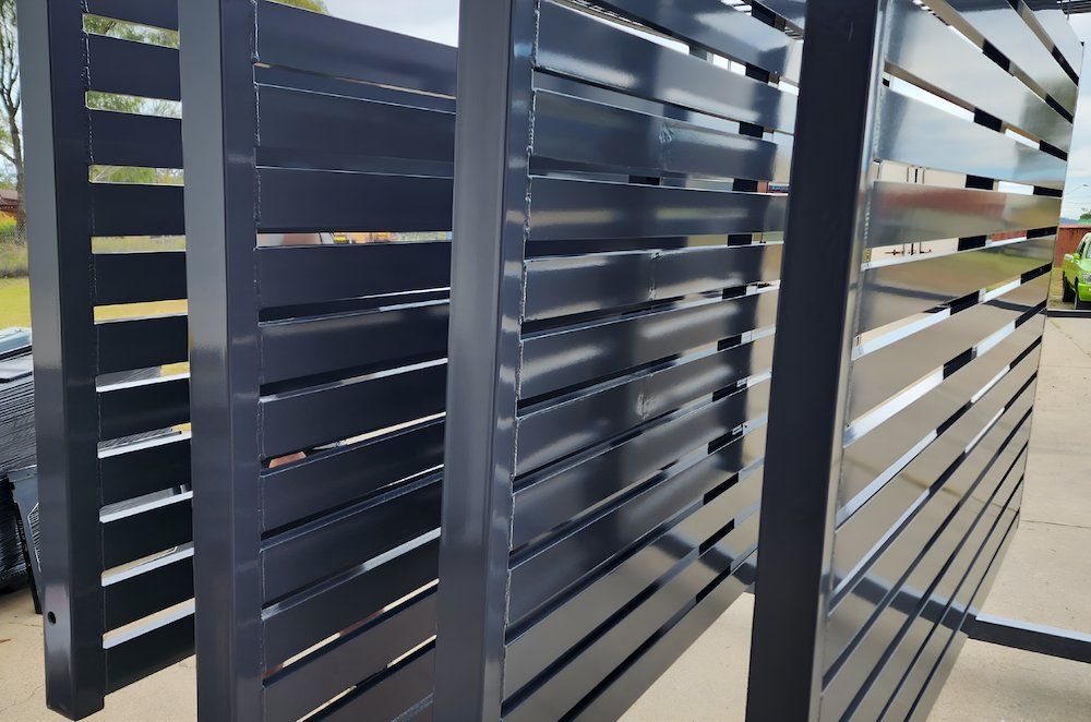 A Black Metal Fence Is Sitting On The Ground — ADK Coatings In Boyne Island, QLD