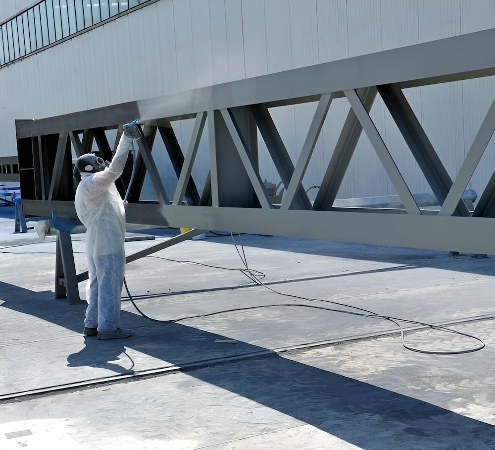 A Man Is Spray Painting A Large Metal Structure — ADK Coatings In Agnes Water, QLD