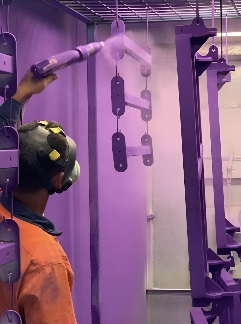 A Man Wearing A Helmet Is Spraying Powder On A Piece Of Metal — ADK Coatings In Bundaberg, QLD