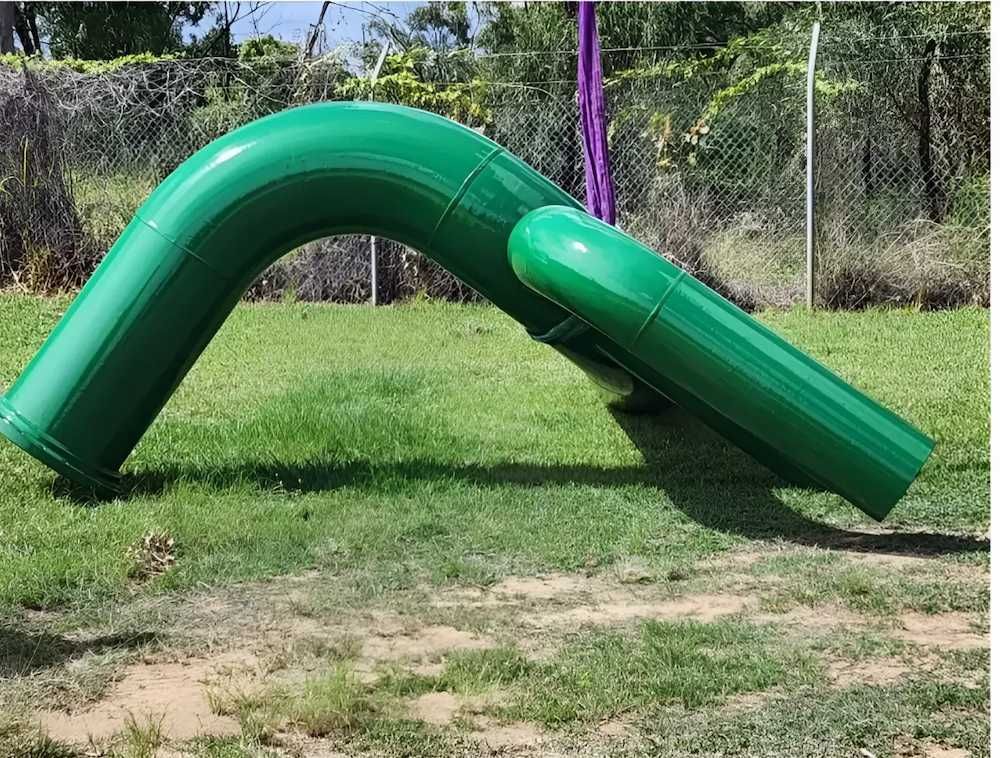 A green pipe is sitting in the grass next to a fence — ADK Coatings In Toolooa, QLD