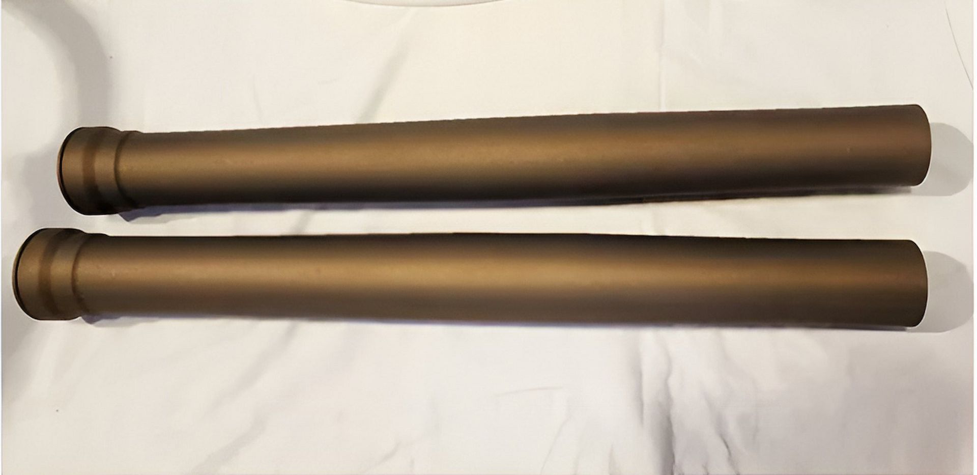 Two Brown Pipes Are Sitting On A White Surface — ADK Coatings In Bundaberg, QLD