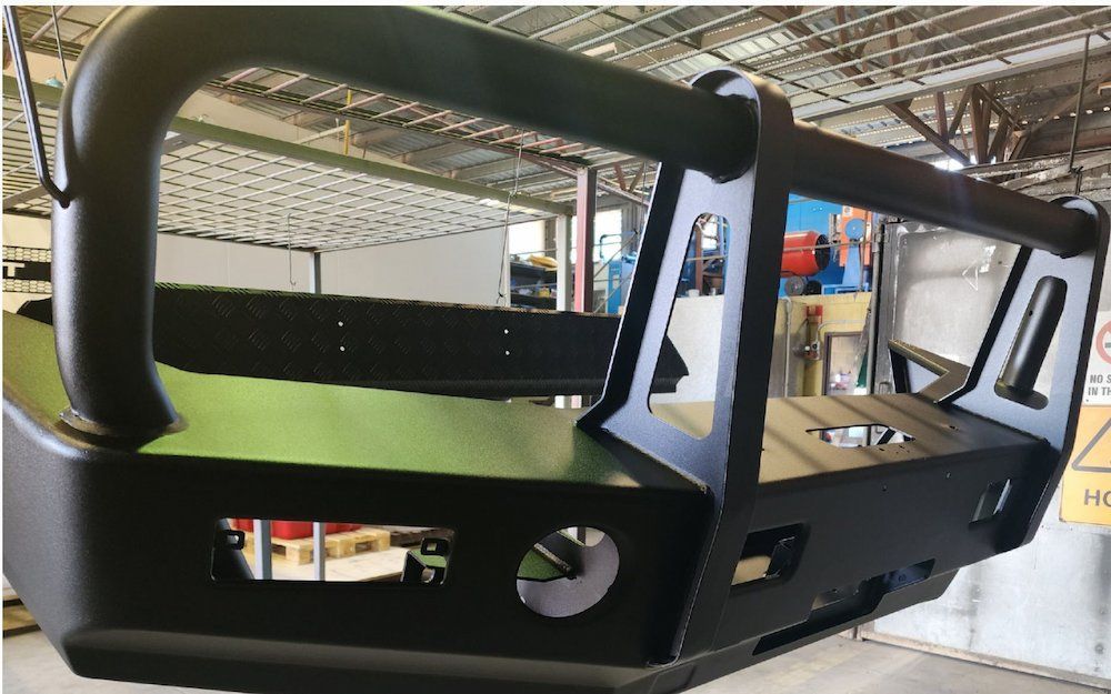 A Black Bumper Is Hanging From The Ceiling Of A Building — ADK Coatings In Toolooa, QLD