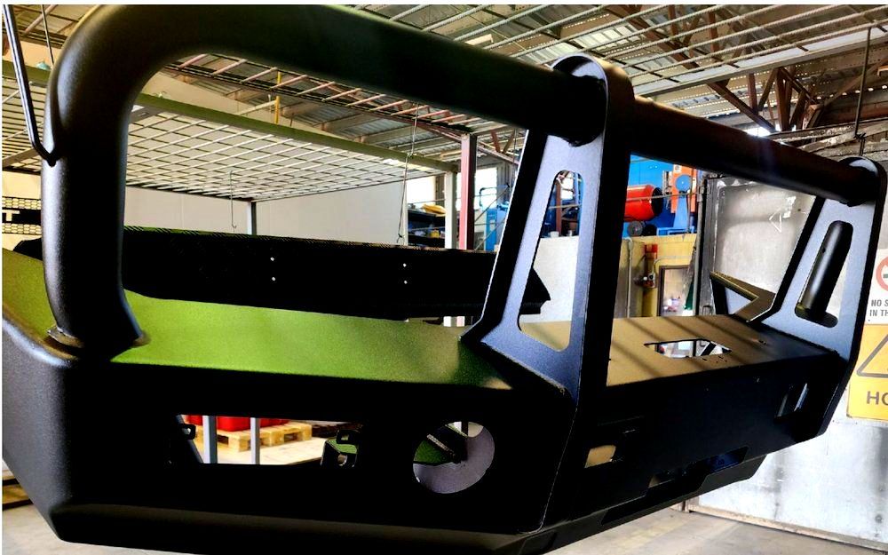 A Black Bumper Is Sitting On Top Of A Green Table In A Warehouse — ADK Coatings In Toolooa, QLD