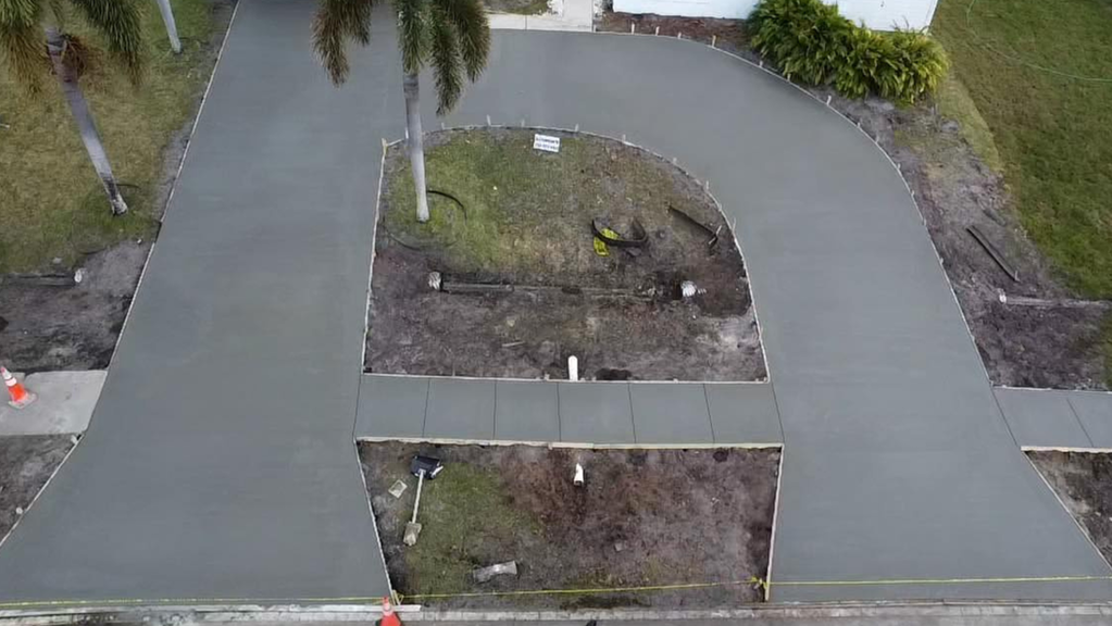 Overhead shot of freshly poured concrete driveway with a central grassy island.