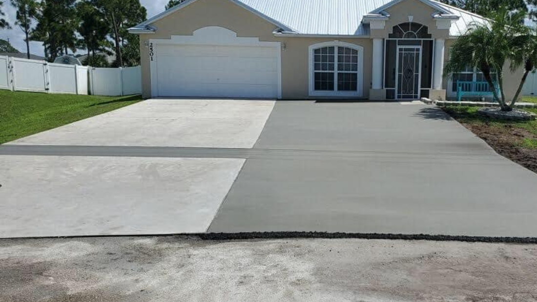 Driveway half-paved with gray concrete, other half old. House in background.