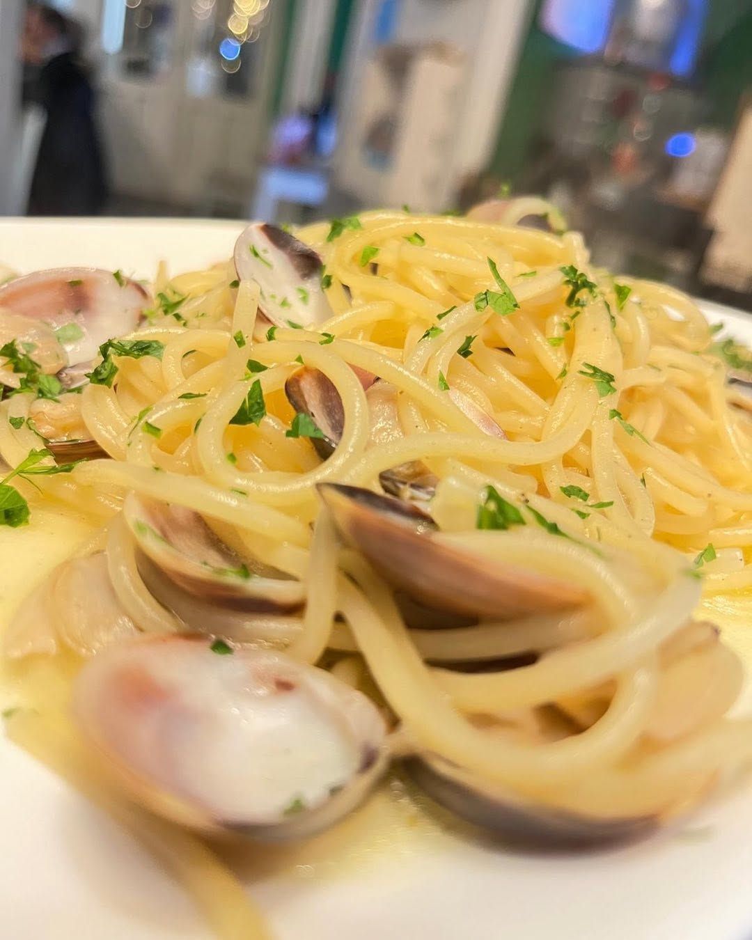 Spaghetti alle vongole con vongole e prezzemolo su un piatto bianco