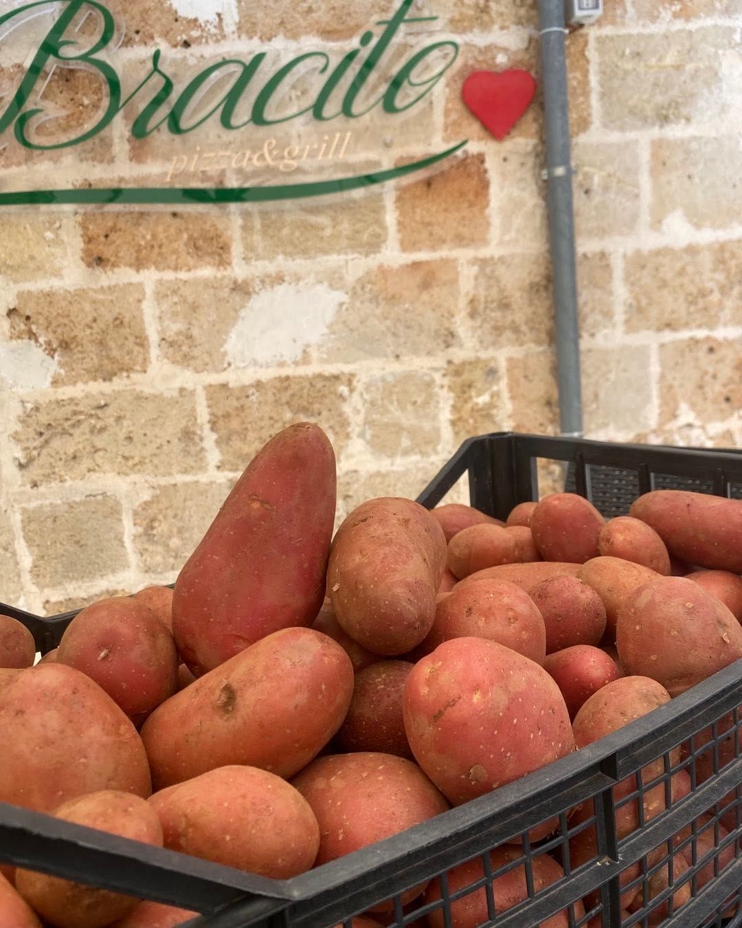 Cassa di patate rosse davanti a un muro di pietra con un cartello «Bradford».