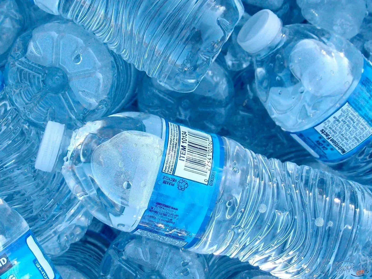 A pile of plastic water bottles with a blue label