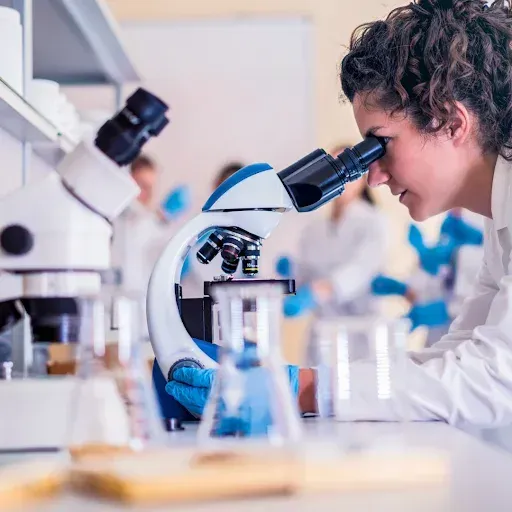 A woman is looking through a microscope in a laboratory.