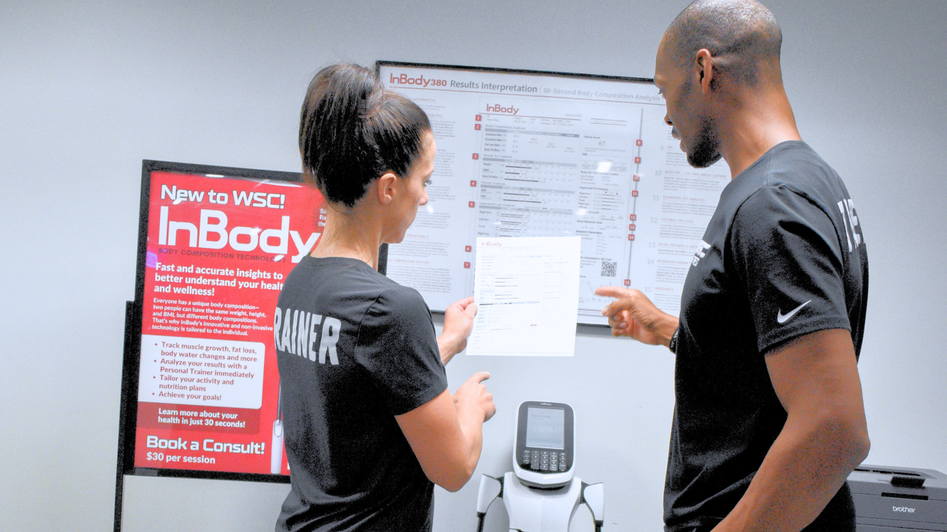 Two people in black shirts reviewing a chart on a wall in a bright room