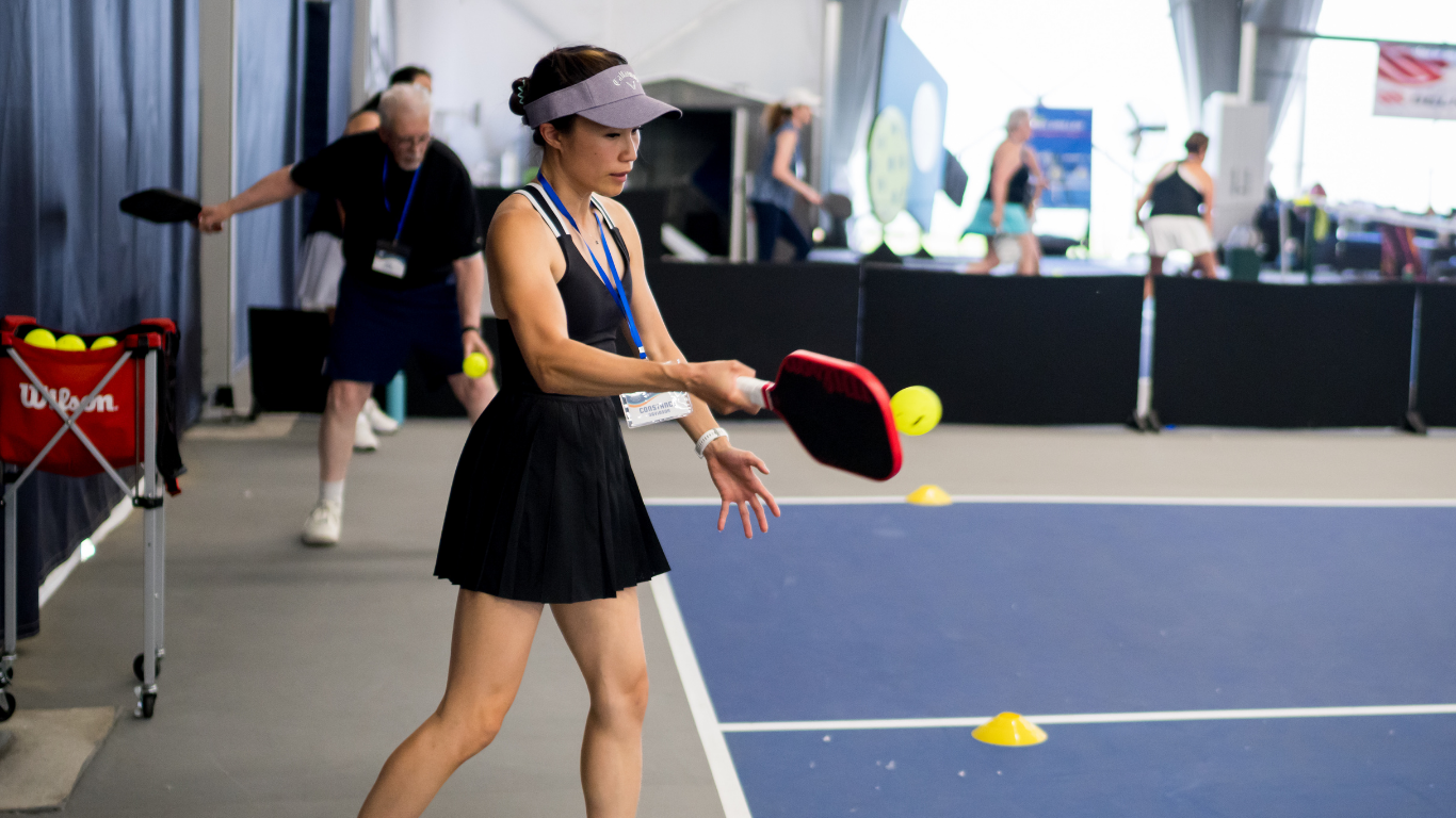 Player with paddle near a yellow ball on an indoor pickleball court