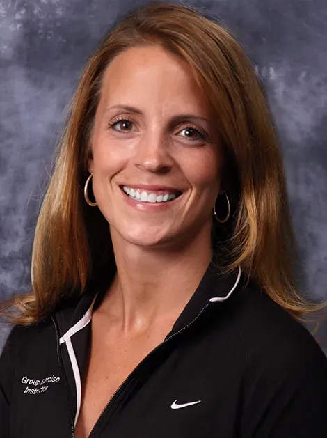 Smiling woman in a black collared shirt against a gray background