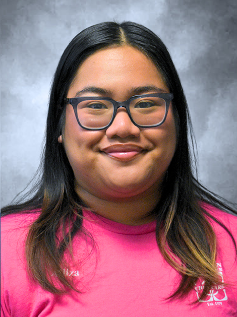 Person smiling in glasses and a bright pink shirt against a gray studio background