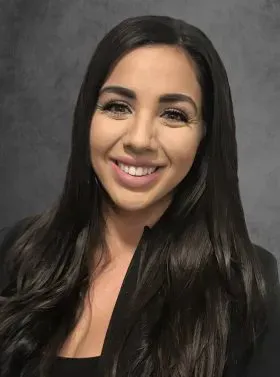 Smiling woman with long dark hair against a gray studio background