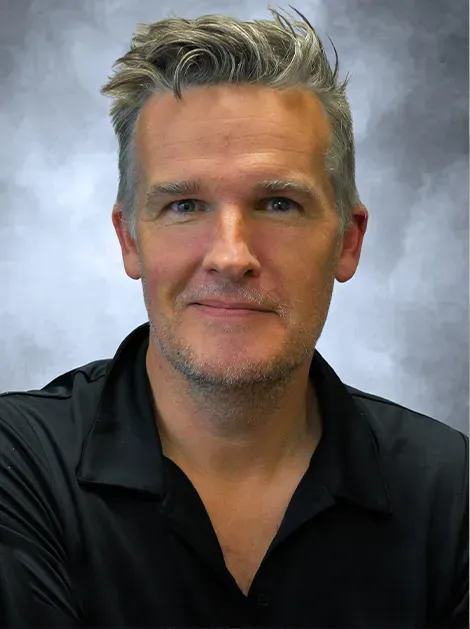 Portrait of a smiling person in a black shirt against a gray studio background