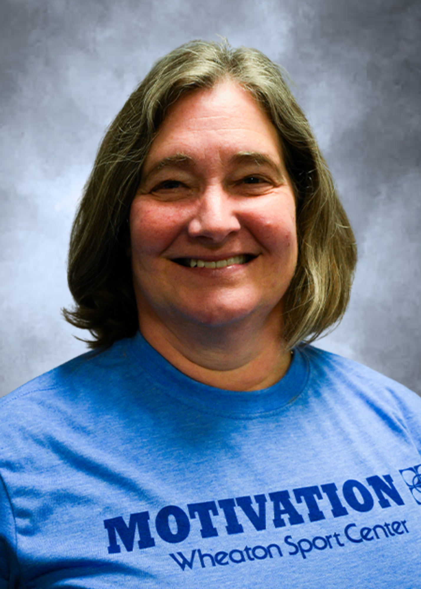 Smiling woman in a blue “Motivation” T-shirt against a gray backdrop